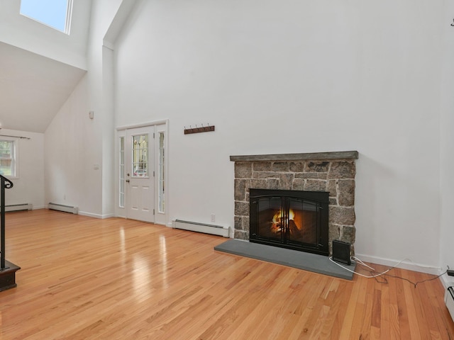 living area with wood finished floors, a healthy amount of sunlight, a fireplace, and a baseboard radiator