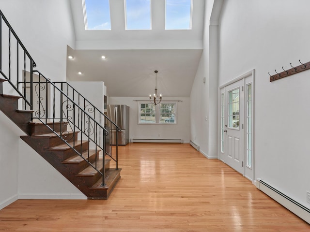 foyer featuring a baseboard heating unit, light wood-style flooring, and a chandelier