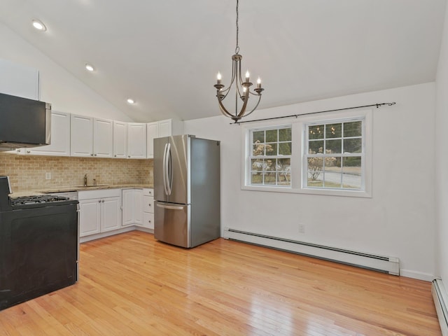 kitchen with gas stove, a baseboard radiator, freestanding refrigerator, a sink, and light countertops