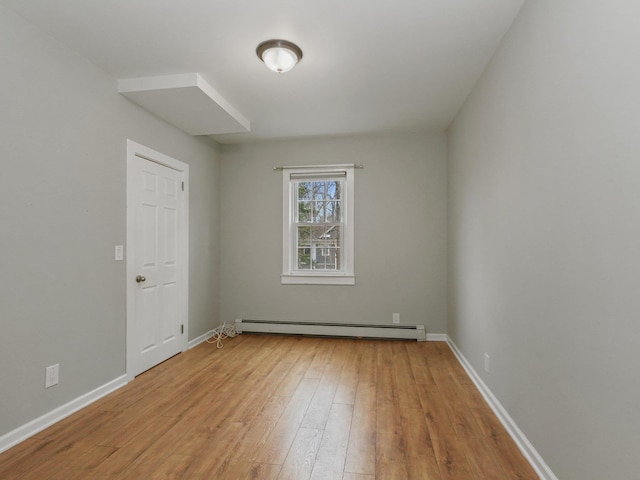 spare room featuring light wood-style flooring, baseboards, and baseboard heating