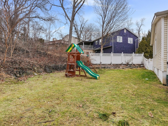 view of playground with a lawn and fence