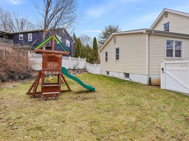 view of playground with a gate, a lawn, and a fenced backyard