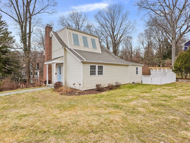 view of home's exterior with a lawn, fence, roof with shingles, and a chimney