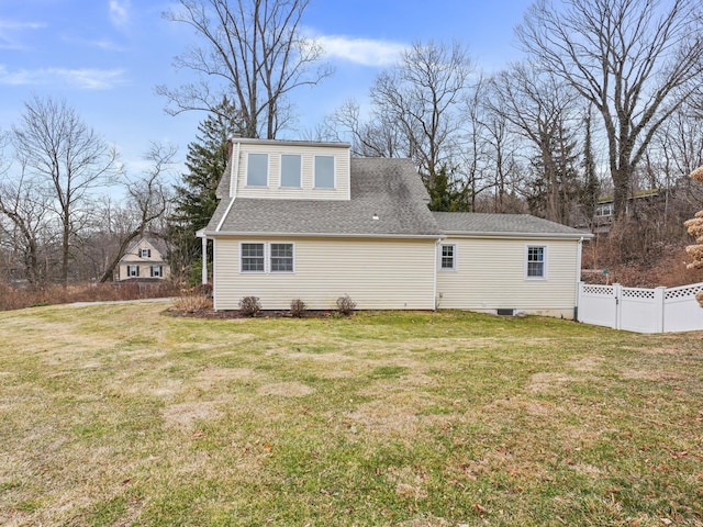 view of side of home with a yard, fence, and a shingled roof