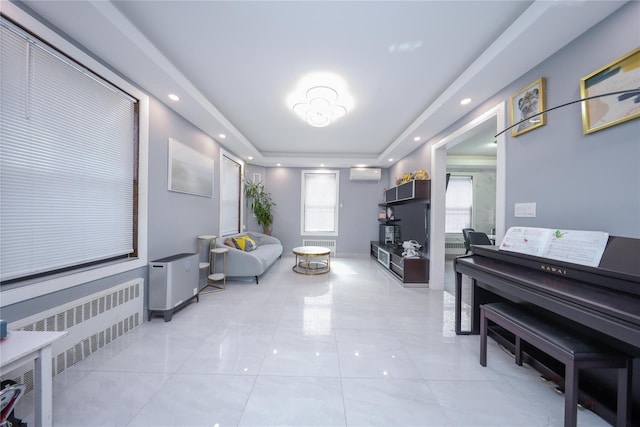 sitting room featuring a tray ceiling, radiator heating unit, a wall unit AC, recessed lighting, and light tile patterned floors