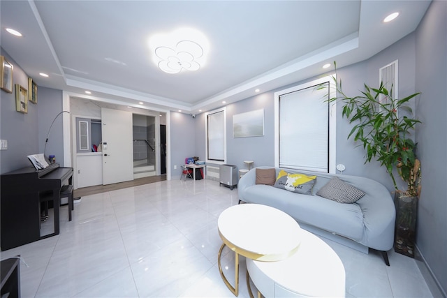 living room featuring recessed lighting, a raised ceiling, and light tile patterned flooring