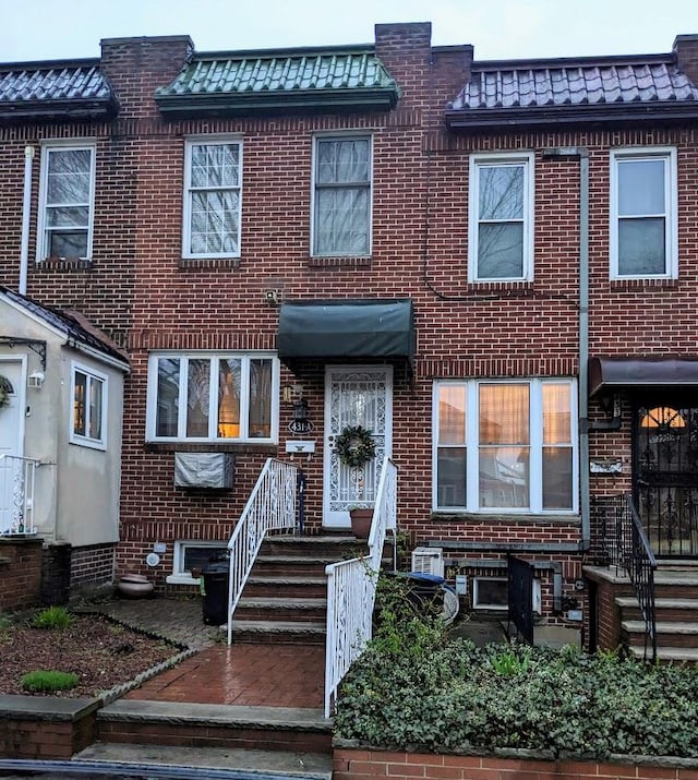 multi unit property with a tile roof, brick siding, and mansard roof