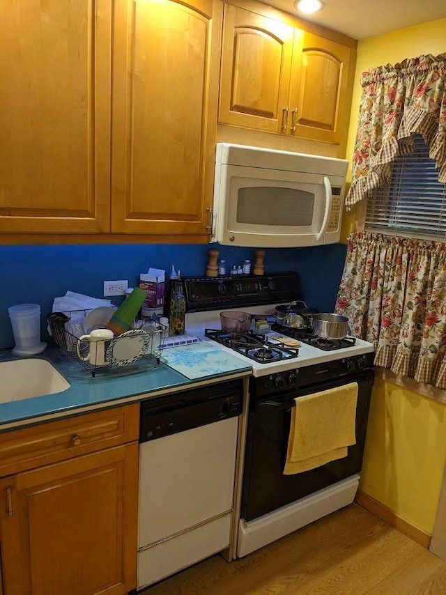 kitchen with white appliances, baseboards, brown cabinets, light countertops, and light wood-type flooring