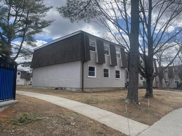 view of side of property with mansard roof and roof with shingles