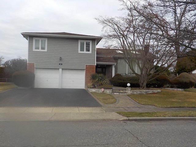 view of front facade with aphalt driveway, a garage, a front lawn, and brick siding