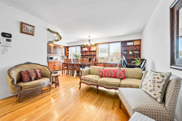 living room featuring cooling unit, light wood finished floors, and a chandelier