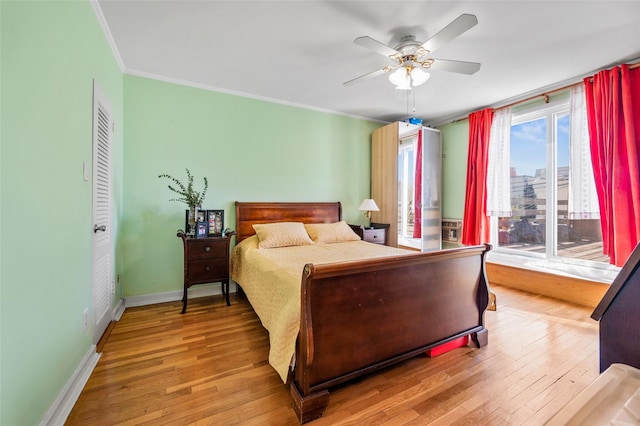 bedroom featuring a ceiling fan, wood finished floors, baseboards, and ornamental molding