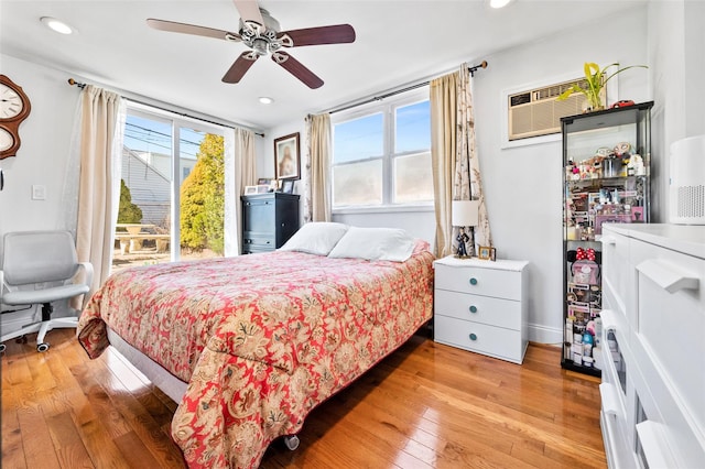 bedroom featuring a wall mounted air conditioner, multiple windows, recessed lighting, and light wood finished floors