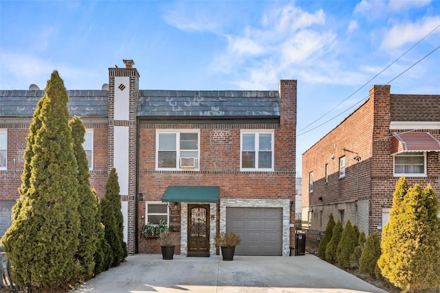 view of property featuring a garage, mansard roof, brick siding, and driveway