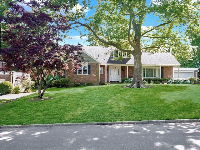 view of front of property with a garage, brick siding, and a front lawn