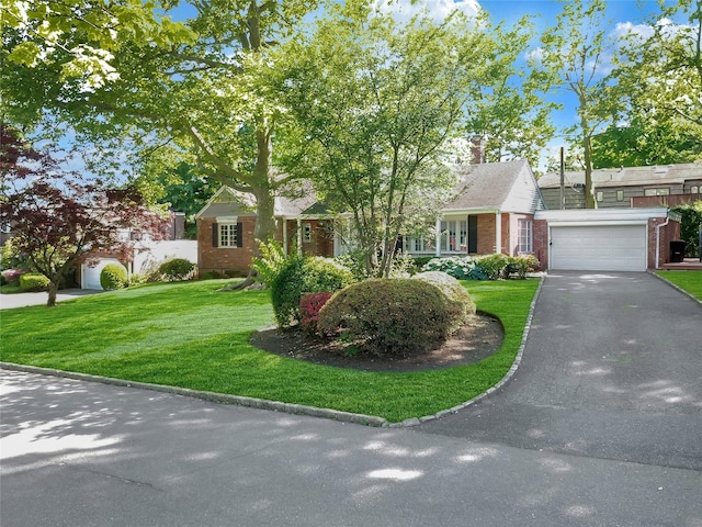 view of front of house featuring aphalt driveway, a front yard, brick siding, and a chimney