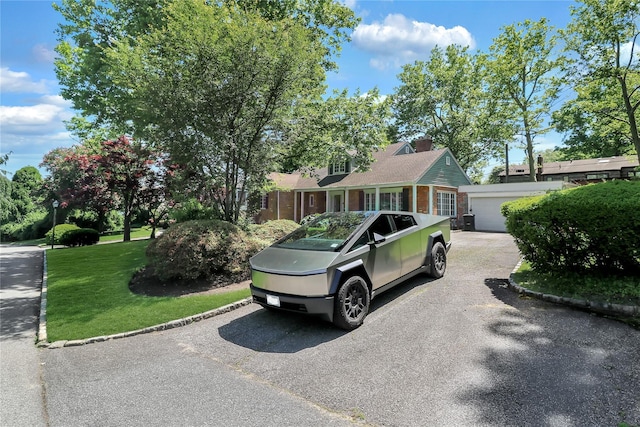 view of front of property featuring a detached garage, a chimney, a front lawn, and an outdoor structure