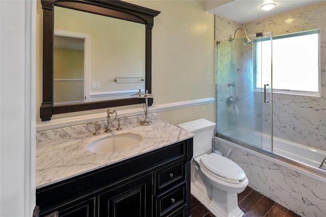 bathroom featuring toilet, enclosed tub / shower combo, wood finished floors, and vanity