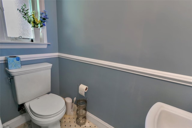 half bath featuring a sink, toilet, and baseboards