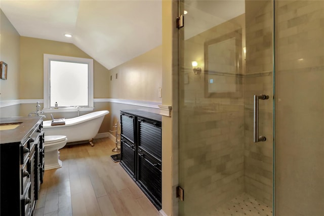 bathroom with a freestanding bath, vaulted ceiling, vanity, a shower stall, and wood finished floors