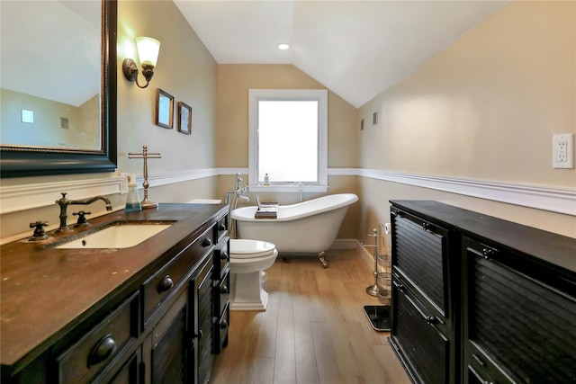 full bath with a soaking tub, toilet, vaulted ceiling, vanity, and wood finished floors