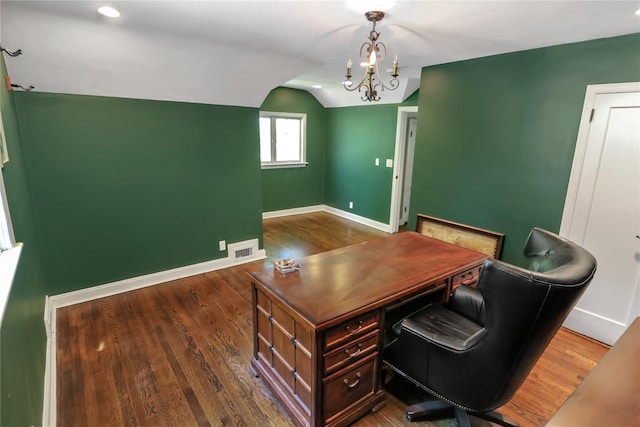 home office with visible vents, an inviting chandelier, vaulted ceiling, wood finished floors, and baseboards