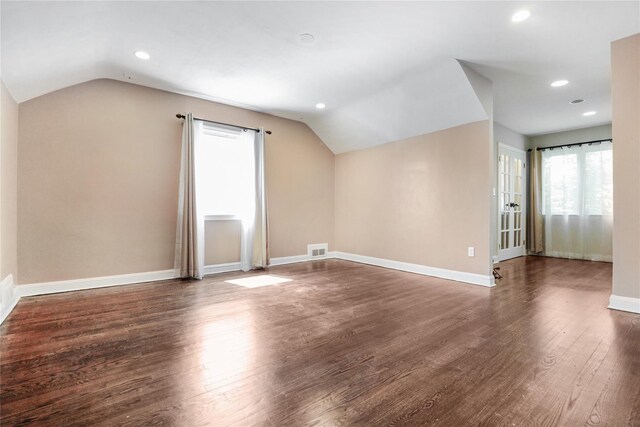 additional living space with visible vents, vaulted ceiling, baseboards, and wood finished floors