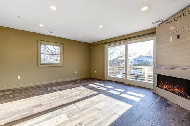 unfurnished living room with visible vents, a wealth of natural light, wood finished floors, and a fireplace