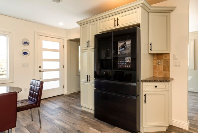 bar featuring decorative backsplash, wood finished floors, freestanding refrigerator, and a wealth of natural light