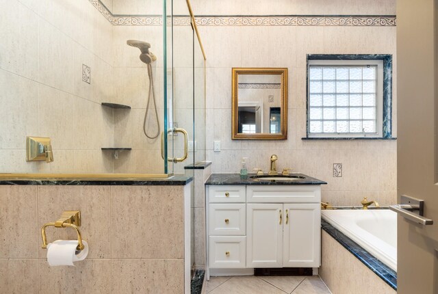 bathroom with vanity, tile patterned floors, tiled tub, tile walls, and a tile shower