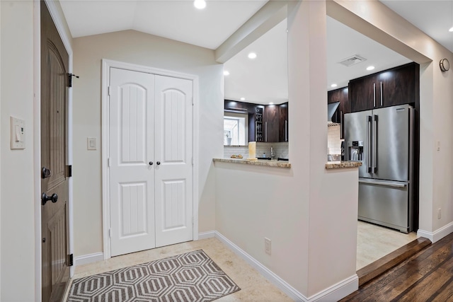 kitchen with lofted ceiling, visible vents, backsplash, dark brown cabinetry, and stainless steel fridge with ice dispenser