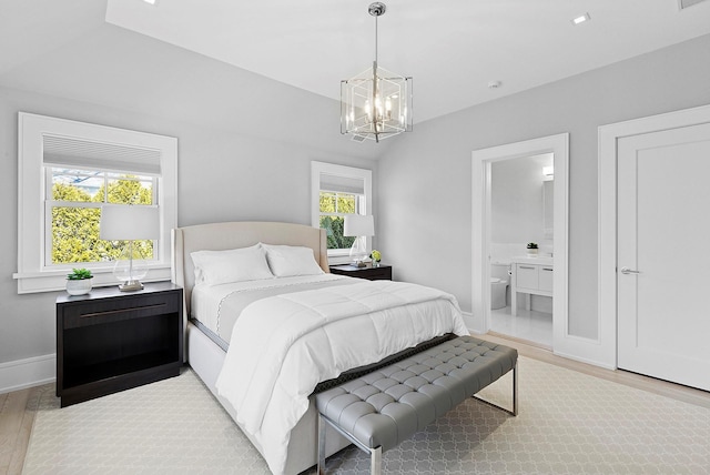 bedroom with light wood-type flooring, a notable chandelier, connected bathroom, and baseboards