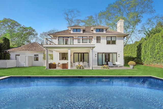 rear view of property featuring an outdoor pool, a patio, a balcony, a yard, and an outdoor living space