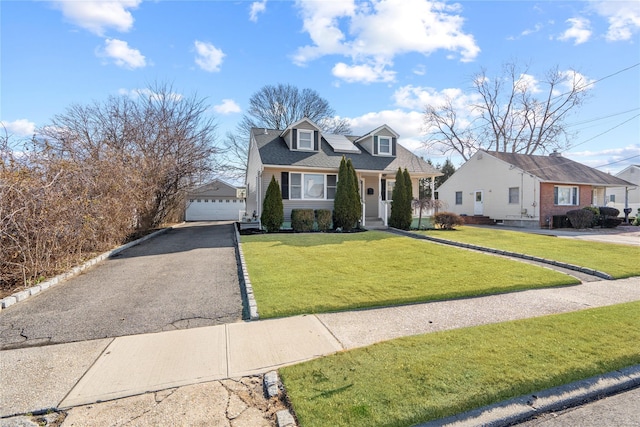 view of front of house featuring a front lawn, a detached garage, and an outdoor structure