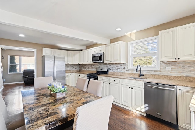 kitchen featuring a sink, backsplash, appliances with stainless steel finishes, and dark wood-style floors