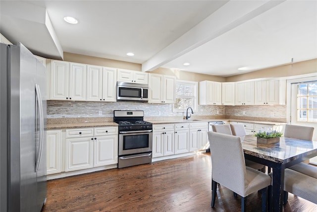 kitchen with beamed ceiling, dark wood-type flooring, backsplash, stainless steel appliances, and white cabinets