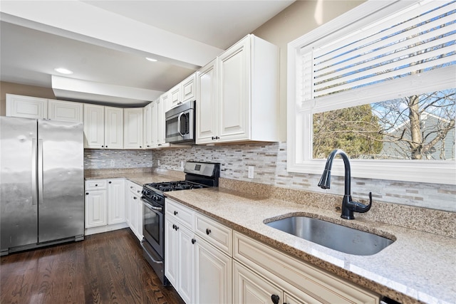 kitchen featuring backsplash, light stone countertops, dark wood finished floors, appliances with stainless steel finishes, and a sink