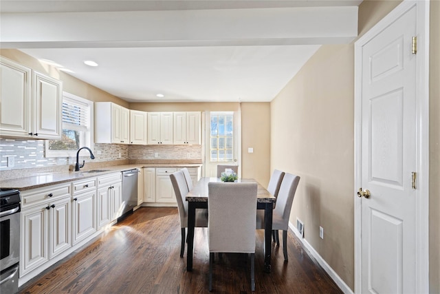 kitchen featuring backsplash, dark wood-style flooring, appliances with stainless steel finishes, and a sink