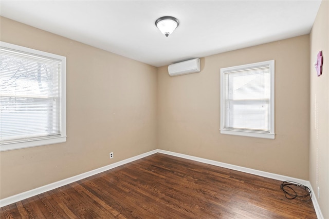 spare room with a wall mounted air conditioner, baseboards, and dark wood-type flooring