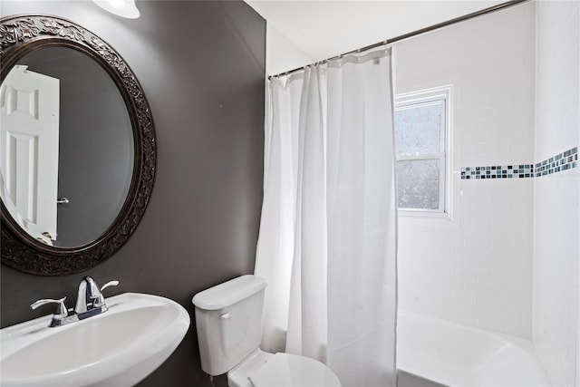 bathroom featuring a sink, toilet, and shower / tub combo with curtain