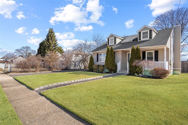 cape cod-style house featuring a front yard, covered porch, and roof with shingles