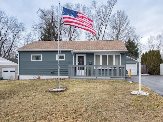 view of front of home with an outbuilding, roof with shingles, a porch, a garage, and a front lawn