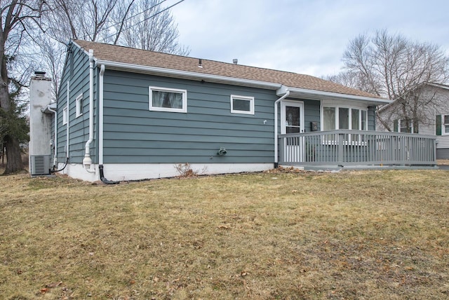 back of house with a shingled roof, a yard, a chimney, and central AC unit