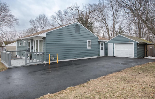 view of property exterior featuring a garage, driveway, a deck, and an outdoor structure