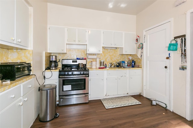 kitchen featuring stainless steel gas range oven, a toaster, a sink, light countertops, and dark wood-style floors