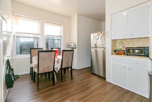 dining area with light wood-style floors, a toaster, and baseboards