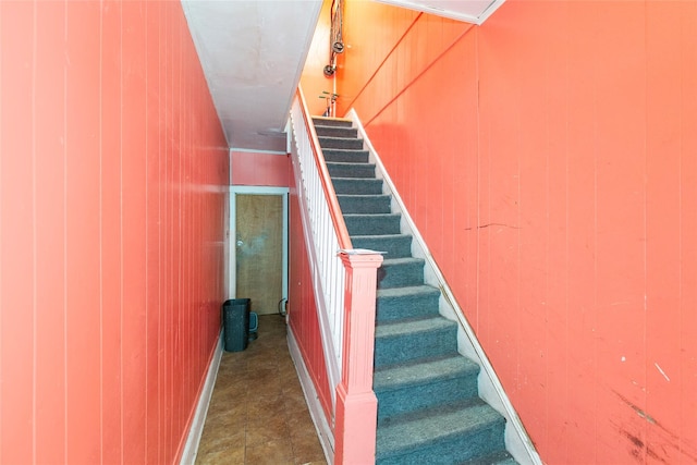 stairs with baseboards and wooden walls