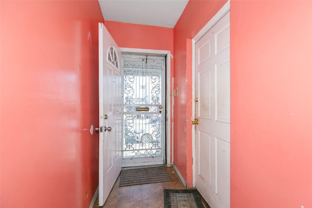 doorway to outside featuring tile patterned flooring, plenty of natural light, and baseboards