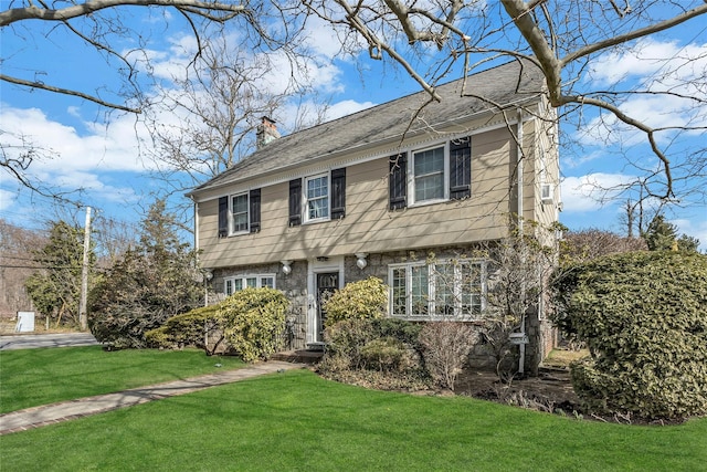 colonial house featuring a front yard and a chimney