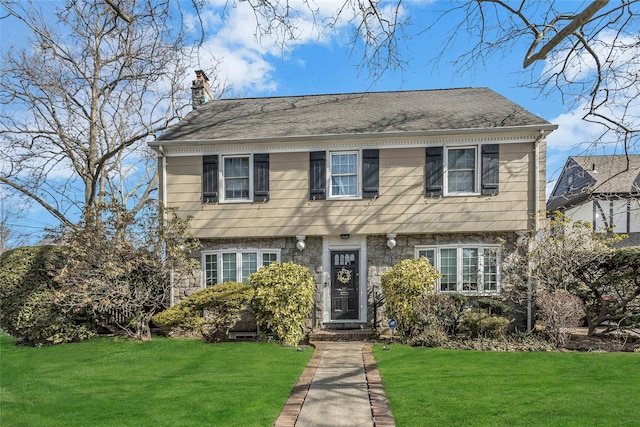 colonial inspired home featuring a chimney and a front lawn